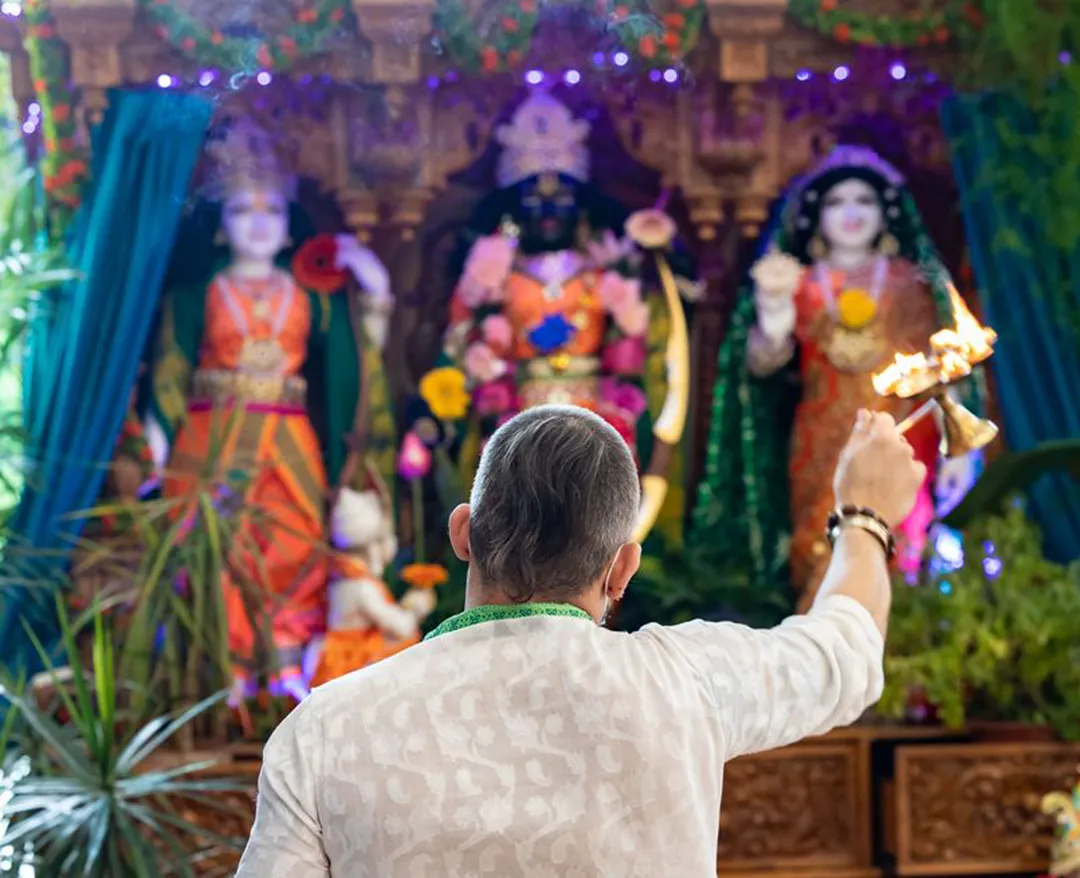 person performing the arati ritual to hindu deities Sita, Rama, Lakshman and Hanuman
