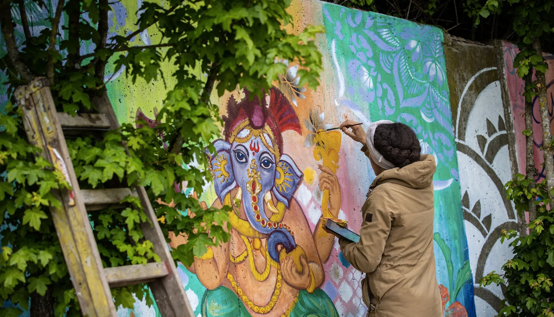 person painting a wall, with colors and calming nature sorroundings